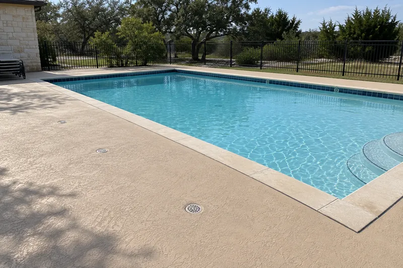 Wide textured deck with drains around a community pool