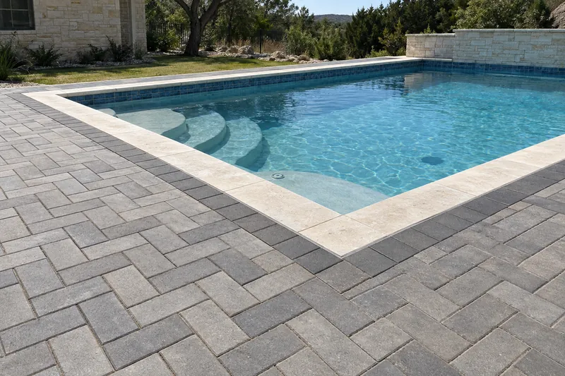 Gray concrete paver deck around a backyard pool