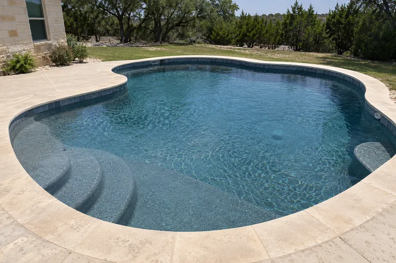 Backyard pool with a dark gray-blue quartz finish and deep blue water