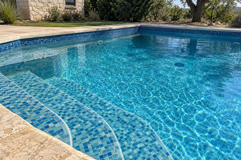 Pool interior covered in blue and aqua glass mosaic tile