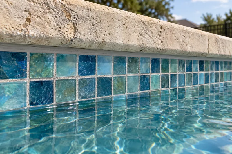 Glass mosaic waterline tile with a flexible sealant joint below the coping
