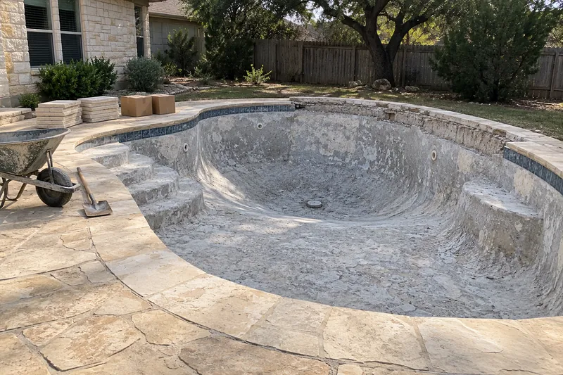 Older pool stripped to bare gunite, its coping coming off for a remodel