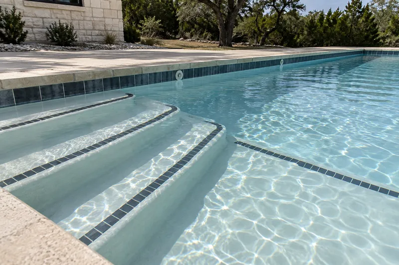 Dark tile stripes marking the step edges in a community pool