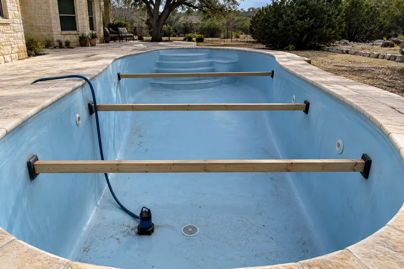 Timber braces across a drained fiberglass pool to hold the walls